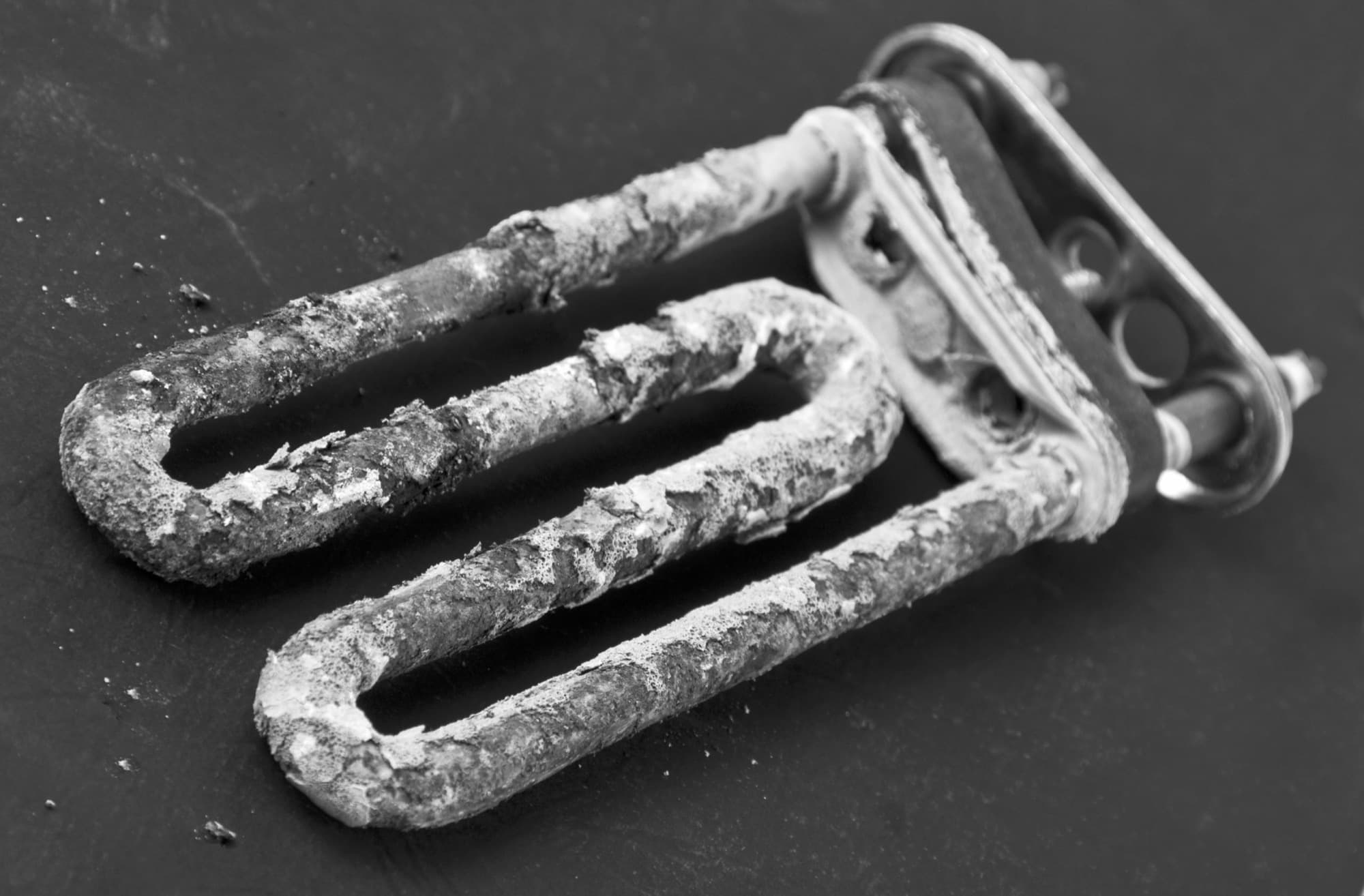 A water heater element completely caked in hard scale after being removed from service